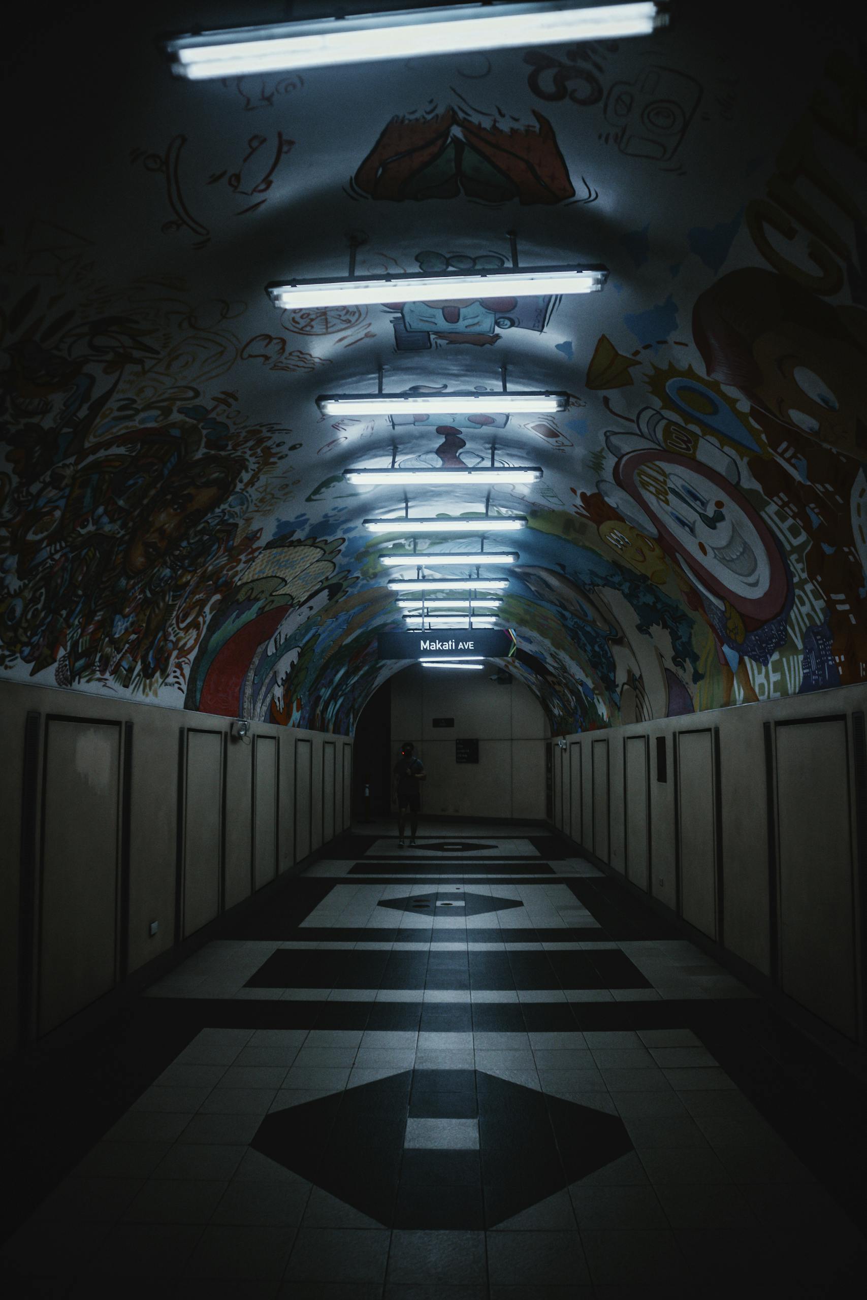 Dimly lit underground passage with vibrant graffiti on walls and ceiling.