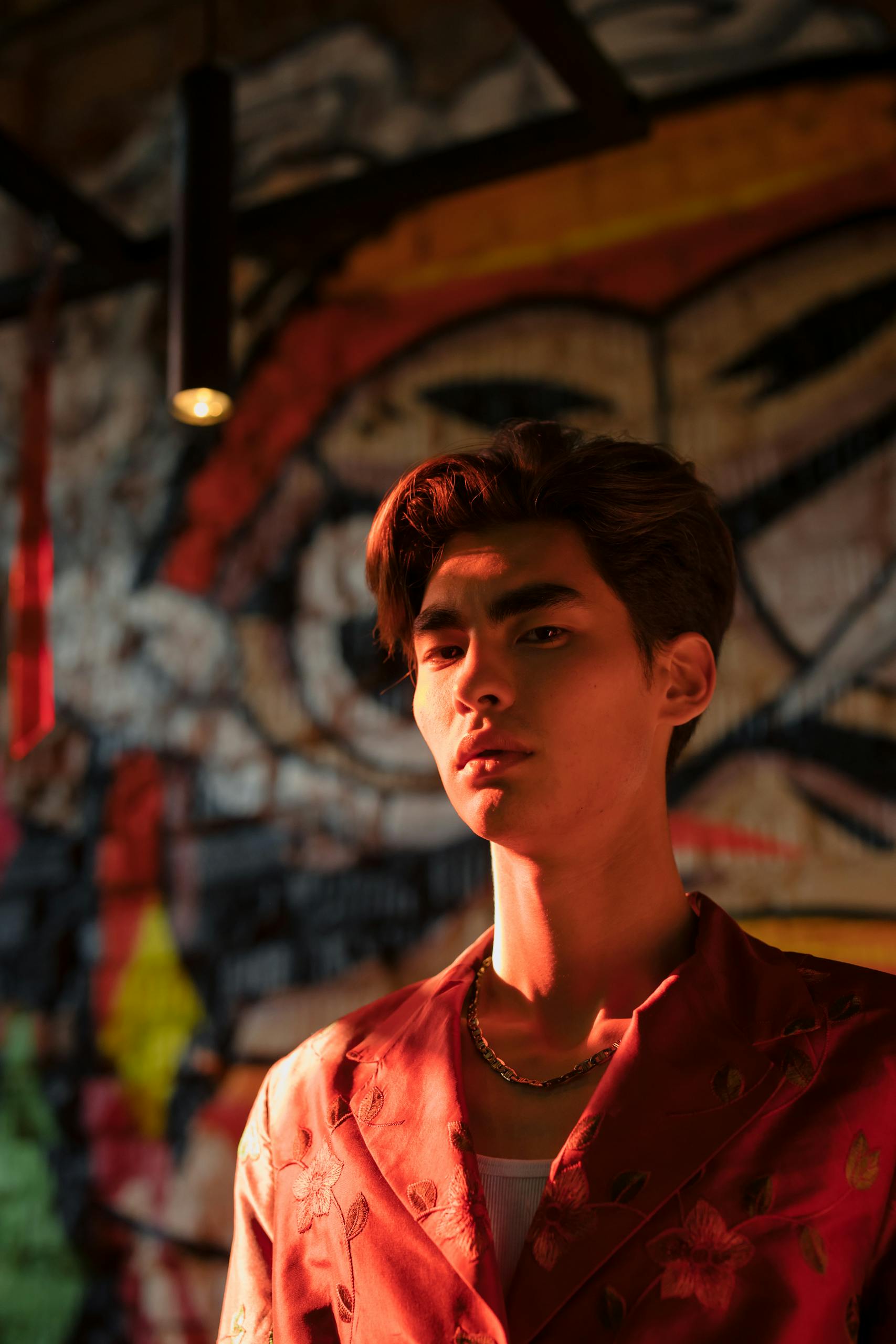 Portrait of a stylish young man with dramatic lighting and graffiti backdrop.